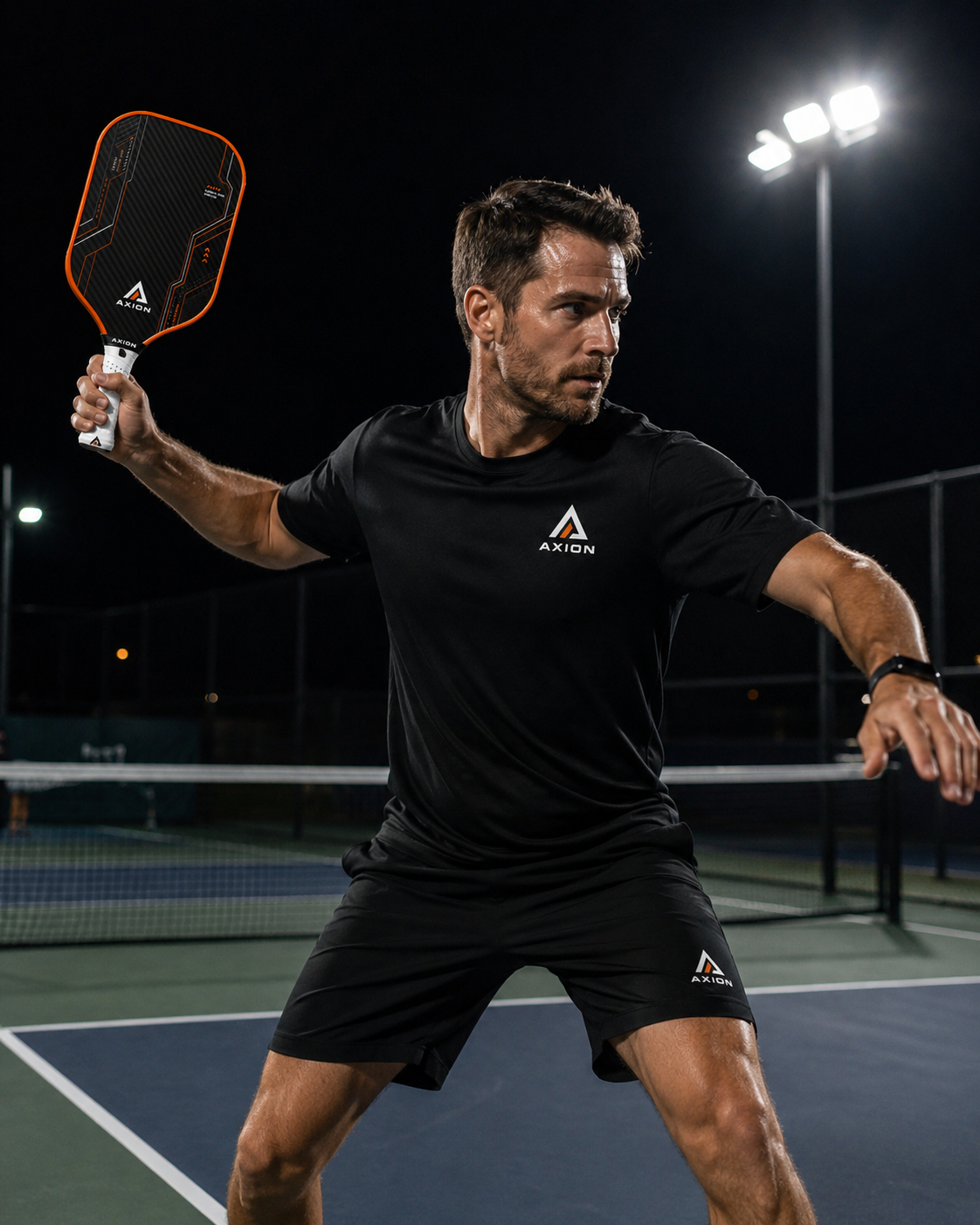 AXION player preparing a shot on a lit pickleball court.